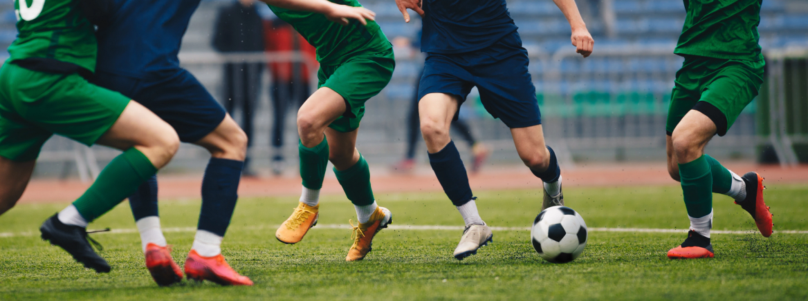 photo of soccer players' feet with one attacker dribbling while being surrounded by defenders.