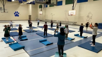Children doing yoga in the gym of the recreation center.