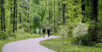 Two people walking on a greenway.