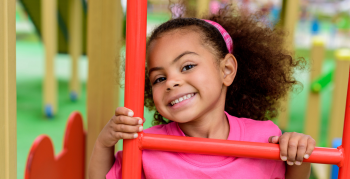 smiling curly african american little child climbing on stairs at playground