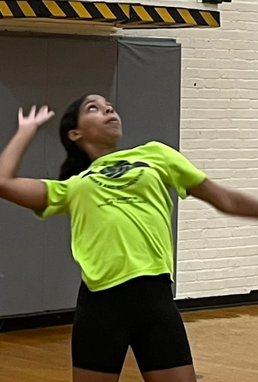 A girl playing volleyball inside a gym.
